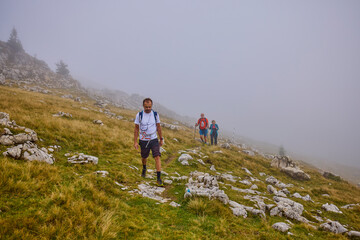 Obraz premium a couple with their grandfather walking in the mountains on a cloudy and foggy day.