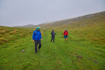Obraz premium a couple with their grandfather walking in the mountains on a cloudy and foggy day.