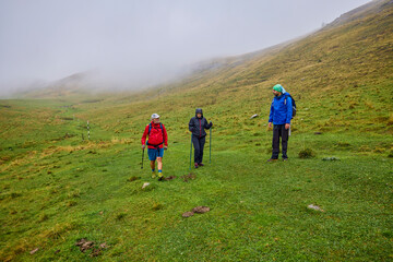 a couple with their grandfather walking in the mountains on a cloudy and foggy day.