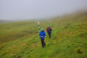 Obraz premium a couple with their grandfather walking in the mountains on a cloudy and foggy day.
