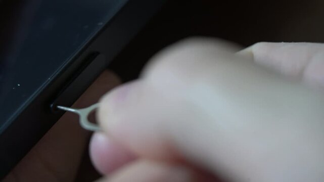 Person taking out and inserting a sim card into back of mobile phone. Sim card in tray being inserted into phone, closeup
