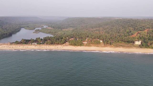 Aerial view of Kelus Kalvi Beach, a stunning sandbar separating a river lagoon from the ocean, backed by a dense tropical forest.