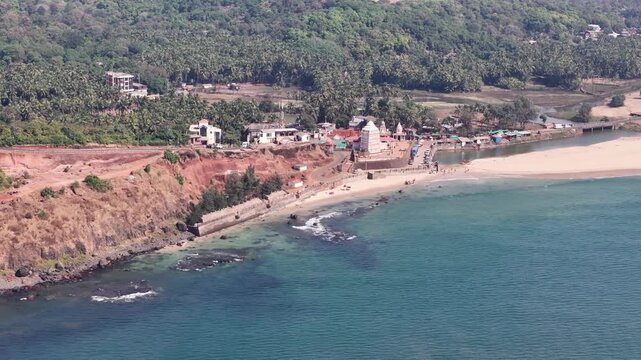 Aerial drone view of the ancient Kunkeshwar Temple, a Hindu mandir located on a beautiful sandy beach on the coast of Maharashtra, India.