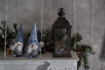 Two dwarf toys in caps on Christmas Eve evening stand on the fireplace