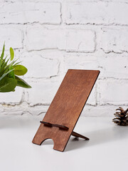 Brown wooden phone holder, on a white table