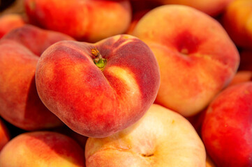 Flat peaches. Juicy ripe peaches. Background of red ripe peaches from figs, agricultural produce, sale at farmers market. Harvest season.