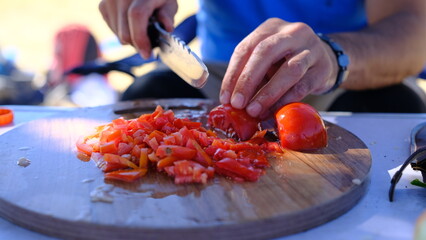 Cooking in nature, chopping tomatoes with a large knife