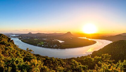 Panoramic sunset view of a winding river valley. Lush greenery surrounds the tranquil waterway, nestled between hills