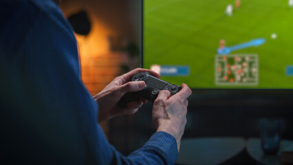 Man Playing an Online Football Match From the Comfort of His Living Room Couch. Male Using a Console Controller, Winning a Video Game Soccer Tournament with a Successful Goal
