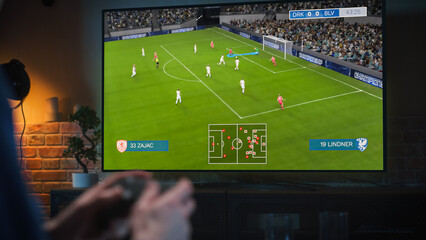 Man Spending Time at Home in the Evening, Playing a Football Video Game on a Big TV Set at Home. Close Up on Male Hands Using a Controller to Defeat a Rival Soccer Team Online