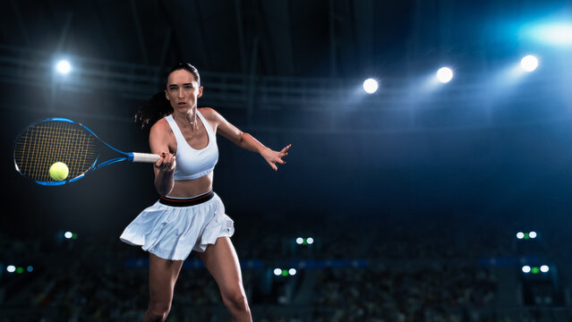 Athletic Female Tennis Player Hitting a Ball Under Spotlights in a Dark Stadium with Spectators. Cinematic Shot Captures a Winning Strong Shot During a Match                    