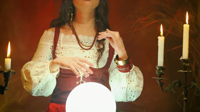 Halloween woman Fantasy witch beautiful gypsy girl, predicts fate crystal ball in dark gothic room. Mystical old art vintage astrology. Fortune teller woman reading future. magic light