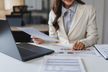 Fototapeta premium Businesswoman analyzing financial charts and documents at office desk