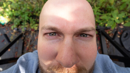 close-up portrait of bald man with intense gaze outdoors