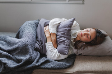 Young woman sleeping peacefully on sofa holding pillow