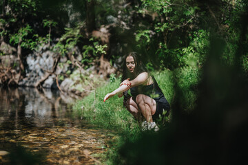 A woman crouching near a forest creek with calm surroundings and lush greenery, representing peace, reflection, and connection with nature.