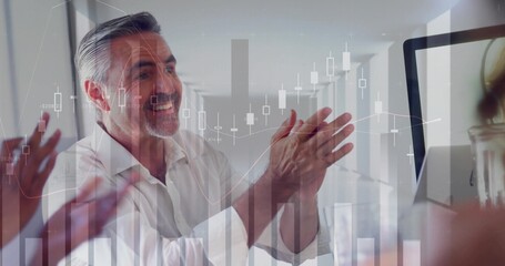 Clapping professionals celebrating business success at desk in office corridor with chart overlay