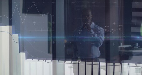 Analyzing data display businessman standing behind glass partition in corporate office, with graphs