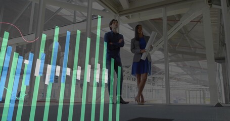 Inspecting factory pair wearing work attire holding plans amid steel columns with chart overlay