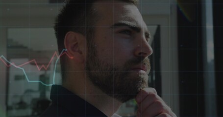 Analyzing businessman wearing blazer resting chin at glass office window, with red and blue charts