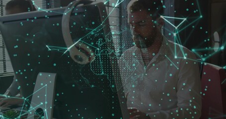 Projecting digital network overlaying colleagues working on monitors in office, with mouse, headset