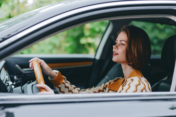 Naklejka premium A woman sits behind the steering wheel of a car, focused on the road with a calm expression, casual sweater and natural light highlighting the interior.