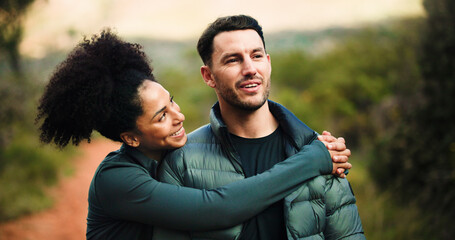Couple, love and hug on hike, forest or bonding for adventure, think and happy in nature or fitness. Outdoor, man and embrace with woman on weekend, affection or care on holiday, healthy and wellness