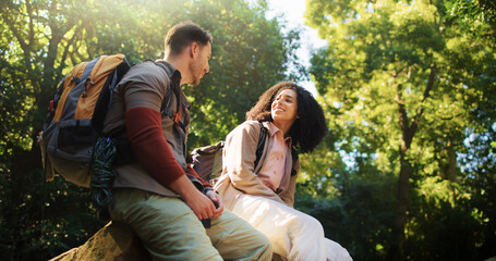 Hikers, talk and couple in nature, relax and break on adventure, forest and love on holiday or trip. Outdoor, people and bonding on journey, backpacking or happy on vacation, low angle and woods