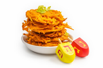 Traditional dreidels, tasty potato latkes for Jewish holiday Hanukkah on white background. Free space for text. Hebrew letters on dreidels say: "Great Miracle Happened Here". 
