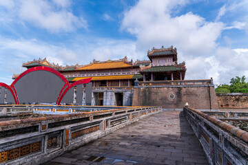 A magnificent brick and stone fortress stands under a bright blue sky, showcasing the intricate and traditional architecture of the Hue Imperial City, rich with history.