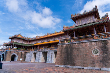 A magnificent brick and stone fortress stands under a bright blue sky, showcasing the intricate and traditional architecture of the Hue Imperial City, rich with history.