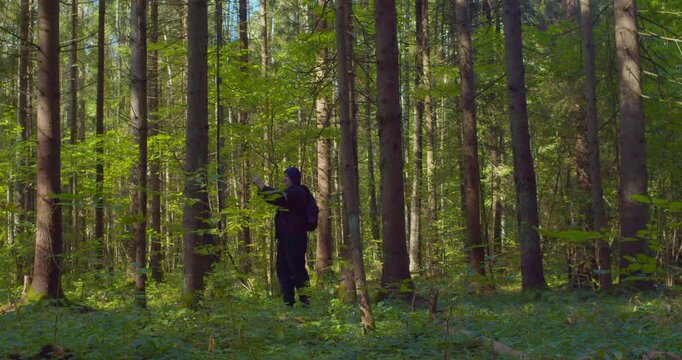 Modern lifestyle. A man backpacker traveling alone in forest wild. Man hiking trip through the green forest with backpack. Man traveler explore while walking in green forest. Travel concept