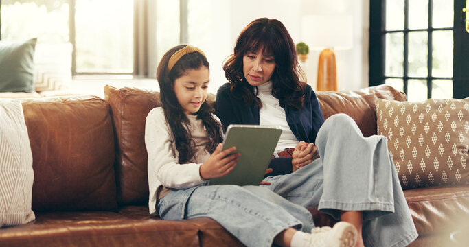 Home, tablet and mother on sofa, girl and bonding together with education games on internet. Learning, parent and family on couch, mama and daughter with tech, network and digital app for puzzle