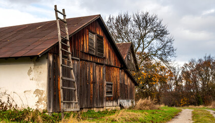 Old wooden barn stands weathered and rustic against a cloudy sky in the countryside, showcasing its timeless charm and rural beauty.