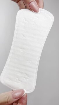 Female hands holding daily panty liner on white background, close-up. Feminine hygiene product for everyday freshness, women&rsquo;s health, menstrual cycle, gynecology, clean lifestyle, medical protection