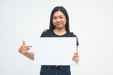 A proud young Asian woman in a half body shot smiling confidently while pointing at the blank white...