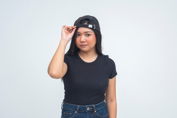A tomboyish young Asian woman in a half body shot wearing her cap backward with a cool and confident look that shows boyish charm. Isolated on a white background.