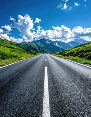Fototapeta premium Upward view of an asphalt road leading towards distant mountains under a bright sky with fluffy white clouds