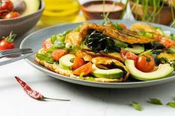 Pancakes with seaweed. Served on a plate with avocado and tomatoes.