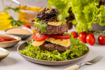 Beef burger without a bun, served on a plate with halloumi cheese.
