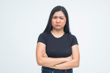 A skeptical young Asian woman standing with her arms folded and furrowed eyebrows, showing a look of disbelief and doubt. Isolated on a white background.