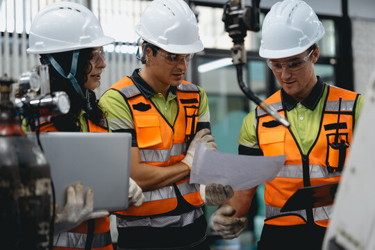 Diverse group of latin engineer working on AI technology in robotics electronics engineering laboratory. Hispanic technician team and colleague research in robot machine futuristic automated control.