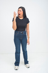 An exhausted young Asian woman captured in a full body shot standing and yawning as she struggles to stay awake from being really tired. Isolated on a white background.