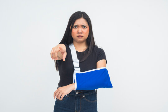 An angry young woman in an arm sling blaming someone for her workplace injury. Threatening to sue for physical damages.