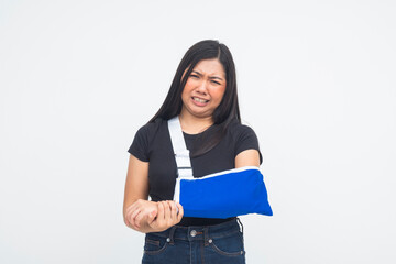 An emotional young Asian woman in a half body shot crying in pain while supporting her injured arm in an arm sling. Isolated on a white background.