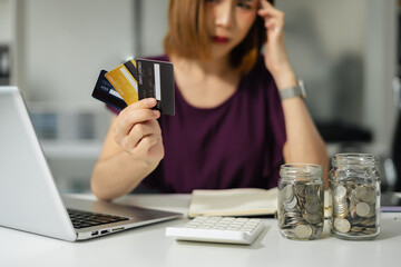 Asian woman stressed over credit card debt, holding bills in frustration.