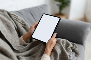 Woman relaxing on a modern sofa using a tablet in a cozy living room setting