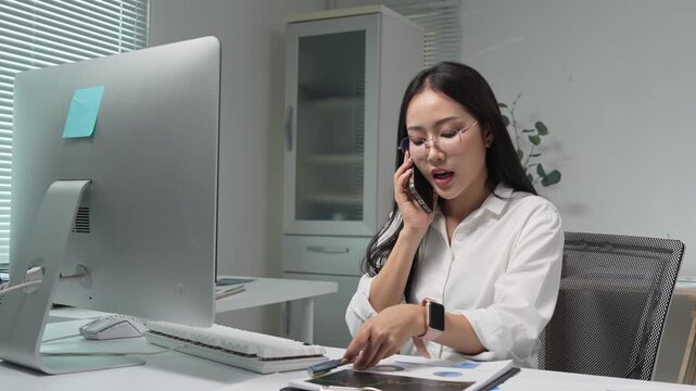 Businesswoman talking on phone and working on computer