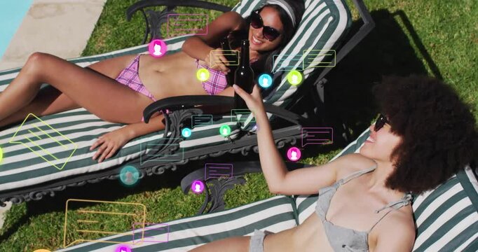 Two female friends sunning poolside picking bottles and clinking under drifting social media icons