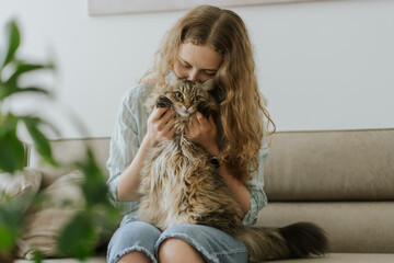 Woman with gray cat on her lap sit on a couch